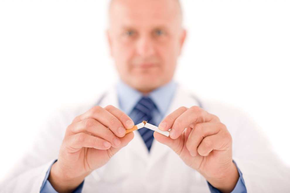 Doctor breaking a cigarette to symbolize stopping smoking before hair transplant
